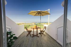 un patio con mesa, sillas y sombrilla en Best Houses 26: Baleal Beach Front Retreat, en Ferrel