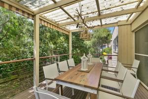 una terrazza con tavolo in legno e sedie bianche di Panoramic Views ad Aireys Inlet Altre 5 foto