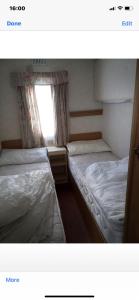 twee bedden in een kleine kamer met een raam bij i13 the chase caravan park in Ingoldmells
