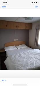 Schlafzimmer mit einem Bett mit weißer Bettwäsche in der Unterkunft i13 the chase caravan park in Ingoldmells