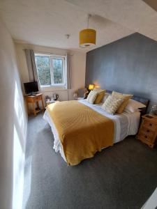 a bedroom with a large bed with a yellow blanket at The Ship Inn in Bardsea