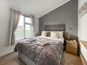 um quarto com uma cama grande com duas toalhas em Alde Lodge - 5 mins from beach with EV Point em Aldeburgh