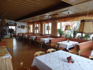 een restaurant met tafels en stoelen met witte tafelkleden bij Dorferwirt in Bramberg am Wildkogel