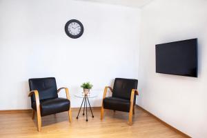 deux chaises noires et une horloge sur un mur dans l'établissement Quartier Mehrblick, à Willingen
