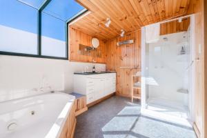 a bathroom with a tub and a shower and a sink at The Boathouse - Freycinet Holiday Houses in Coles Bay +52 photos