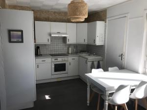 - une cuisine avec des placards blancs, une table et des chaises dans l'établissement Ambleteuse appartement vue mer, à Ambleteuse