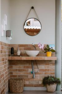 uma casa de banho com um lavatório e um espelho numa parede de tijolos em João de Barro camping e suítes em Alto Paraíso de Goiás