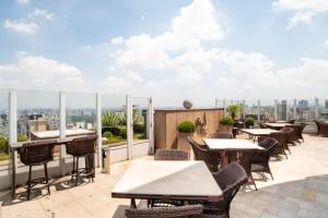 a patio with tables and chairs on the roof of a building at FLAT PRIME II REGIÃO DA PAULISTA JARDINS in Sao Paulo