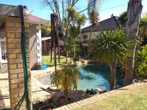 a backyard pool with palm trees and a house at Prince Alfreds in Caledon