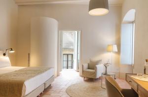a bedroom with a bed and a chair and a window at Can Mascort Eco Hotel in Palafrugell