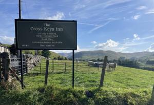 een bord voor de kruissleutels herberg met schapen in een veld bij Cross Keys Inn in Penrith