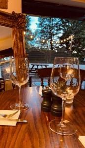 dos copas de vino sentadas sobre una mesa de madera en Cross Keys Inn en Penrith