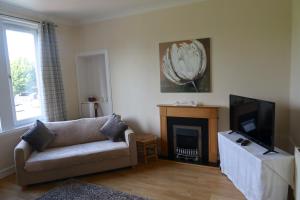 a living room with a couch and a fireplace at Large Apartment near the Beach & World Class Golf in Methil