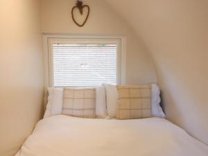 a bed in a room with a window with white pillows at Larch in Uttoxeter