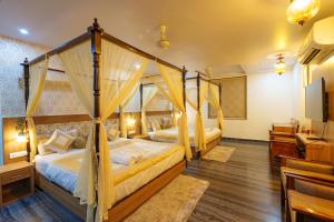 a bedroom with two canopy beds and a television at Trimrooms Mount Blue in Jaipur