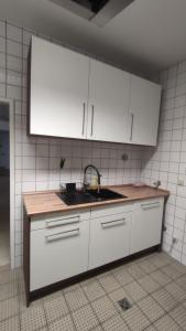 a kitchen with white cabinets and a sink at Zimmer in Ramstein in Ramstein-Miesenbach