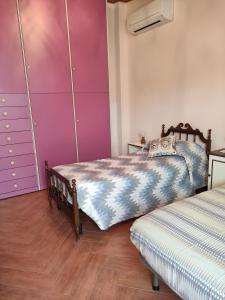 - une chambre avec 2 lits et des murs violets dans l'établissement Casa del pozzo, à Furci Siculo