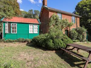 uma casa verde com uma mesa de piquenique em frente em Warren Cottage em Leavenheath