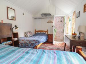 ein Schlafzimmer mit einem Bett und einem Fernseher in einem Zimmer in der Unterkunft Warren Cottage in Leavenheath