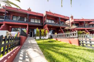 ein rotes Gebäude mit einem Zaun und einem Hof in der Unterkunft Casa Martín. in Playa del Aguila