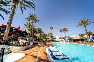 een zwembad met palmbomen in een resort bij Casa Martín. in Playa del Aguila