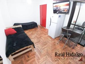 Habitación con cama, mesa y nevera. en Departamento Mar del plata en Mar del Plata