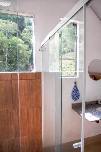 a shower with a glass door and a window at Oca Roça in Delfim Moreira