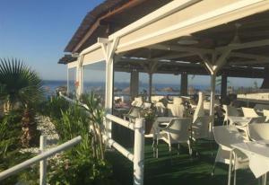 un restaurante con sillas blancas y el océano en el fondo en Sea front house, en Torre del Mar