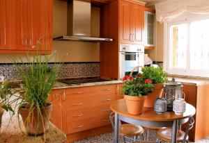 una cocina con armarios de madera y una mesa con plantas en Sea front house, en Torre del Mar