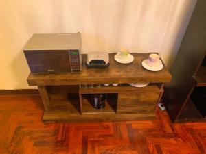 - une table en bois avec un four micro-ondes et 2 tasses sur les assiettes dans l'établissement Iguana Haus Lima, à Lima