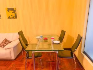 un salon avec une table et des chaises en verre et un canapé dans l'établissement Iguana Haus Lima, à Lima