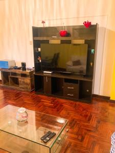 Iguana Haus Lima في ليما: غرفة معيشة مع تلفزيون كبير وطاولة زجاجية
