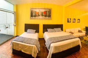 two beds in a room with yellow walls at Iguana Haus Lima in Lima