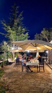 a group of people sitting at a table under an umbrella at La Quercia in Arbus