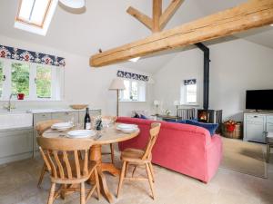 a kitchen and living room with a table and a red couch at Barley Cottage in Cheriton