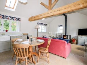 Il comprend une cuisine et un salon avec une table et un canapé rouge. dans l'établissement Barley Cottage, à Cheriton