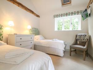 a bedroom with two beds and a chair and a window at Barley Cottage in Cheriton