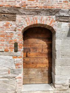 une porte en bois dans un mur de briques dans l'établissement Domus Acaja, à Pignerol