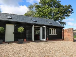une maison noire avec une allée en gravier dans l'établissement Barley Cottage, à Cheriton