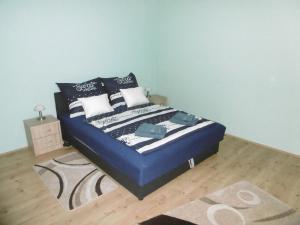 a bedroom with a bed with blue sheets and pillows at Dia Apartman Pécs in Pécs