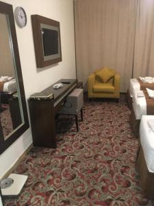Sky View Hotel, Madinah في المدينة المنورة: غرفة في الفندق بها مكتب وسرير وكرسي