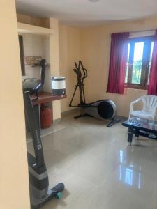 Zimmer mit einem Fitnessraum mit einem Laufband und einem Schreibtisch in der Unterkunft NeelRatna Bed And Breakfast in Shirdi