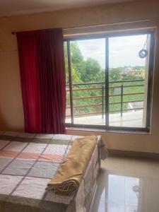 a bedroom with a bed and a large window at NeelRatna Bed And Breakfast in Shirdi