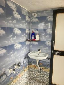 a bathroom with a sink with clouds on the wall at NeelRatna Bed And Breakfast in Shirdi
