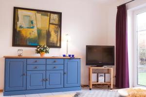 Haus Tjalk Ferienhaus Tjalk links في نورديش: خزانة زرقاء في غرفة المعيشة مع تلفزيون