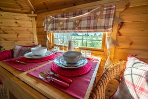a table with two cups and plates on top of it at Hatters Meadows Glamping in Ely