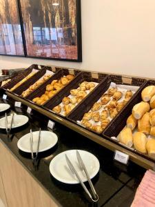 a buffet with a bunch of donuts and plates on a counter at Legacy Hotel Guaratinguetá - Ao lado de Aparecida -SP in Guaratinguetá