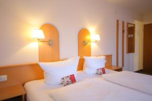 a bedroom with two beds with white pillows and lamps at Hotel Zum Prinzen Sinsheim in Sinsheim