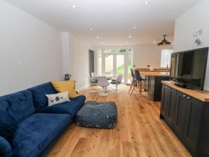 ein Wohnzimmer mit einem blauen Sofa und einer Küche in der Unterkunft Chelsea House in Melton Mowbray