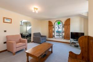 a living room with a table and chairs and a tv at Tregurrian Villas in Newquay